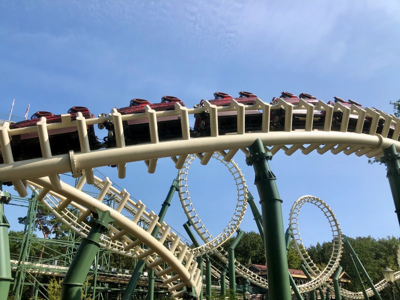 Looping roller coaster and train car passing by on a white and green track