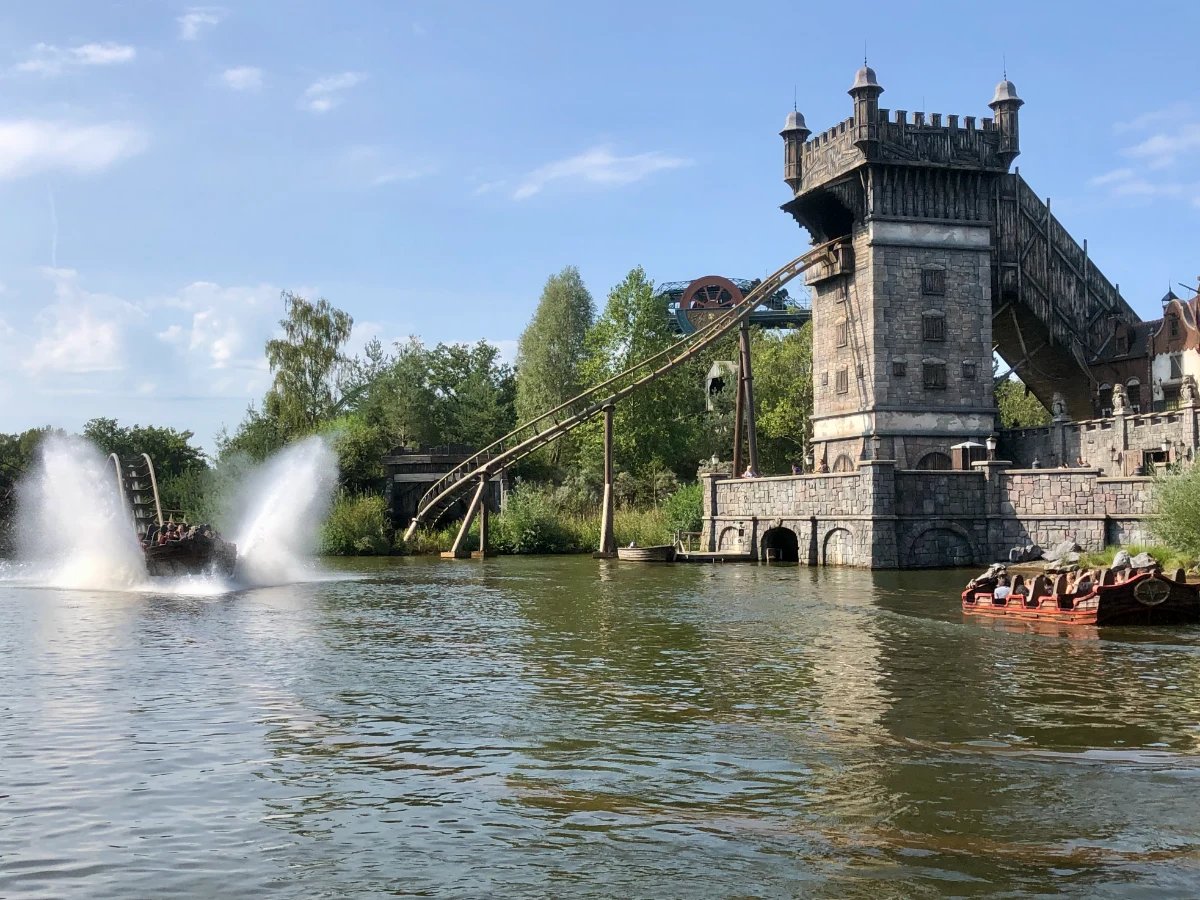 Water ride with car splashing into a lake and a medieval tower