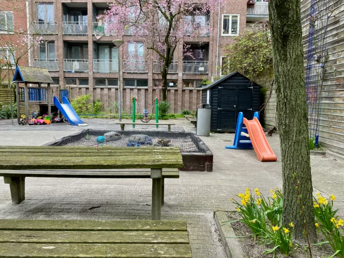 Courtyard playground with play house, slides, covered sandbox, picnic table and spring flowers