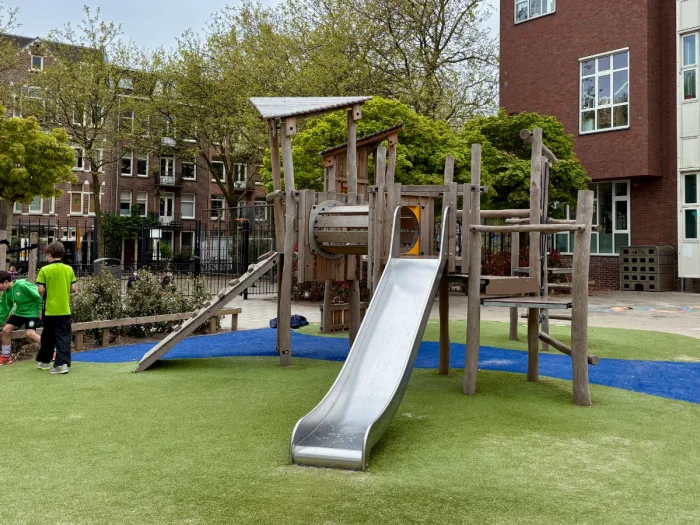 Wooden climbing structure with slide, ladders, ramp on bright green and blue astroturf