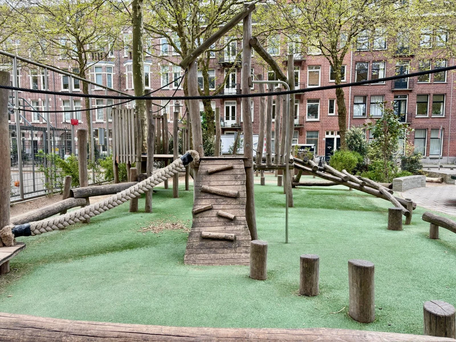 Wooden natural playground in residential urban area with climbing ramps, tight rope, balance course