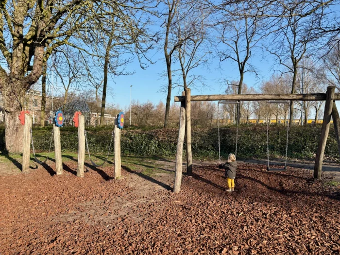 Playground with wooden swing set and two smaller toddler swings with flower decorations