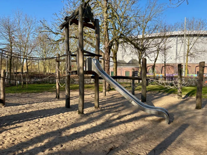 Playground with wooden climbing structure with rope bridge and slide