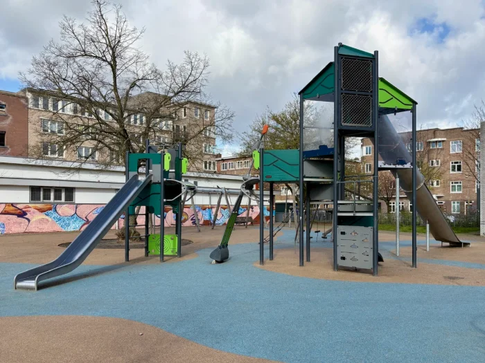 Urban playground with two modern green and metal climbing structures with rope ladders and slides