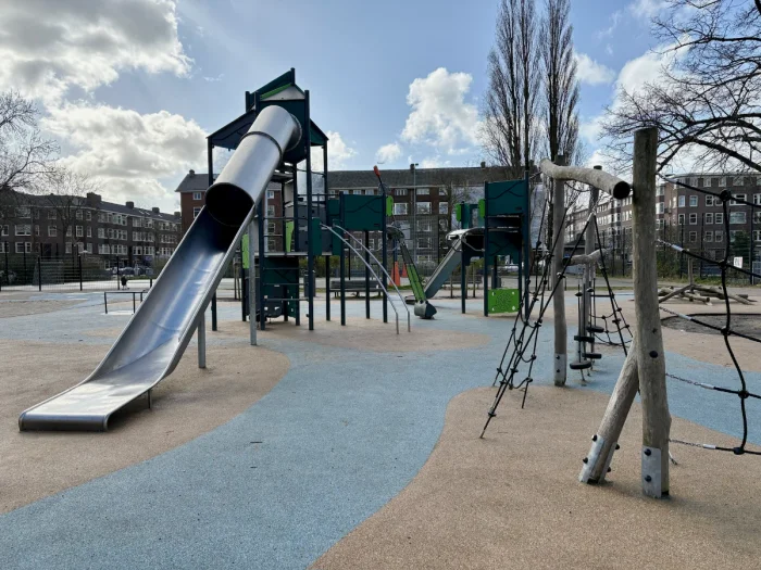 Playground in urban setting with large metal slide and climbing nets