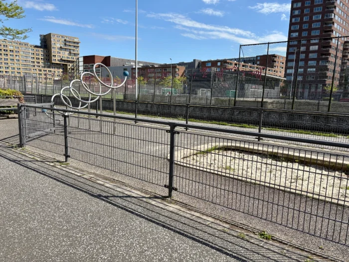 Fenced in sand pit and metal climbing spiral