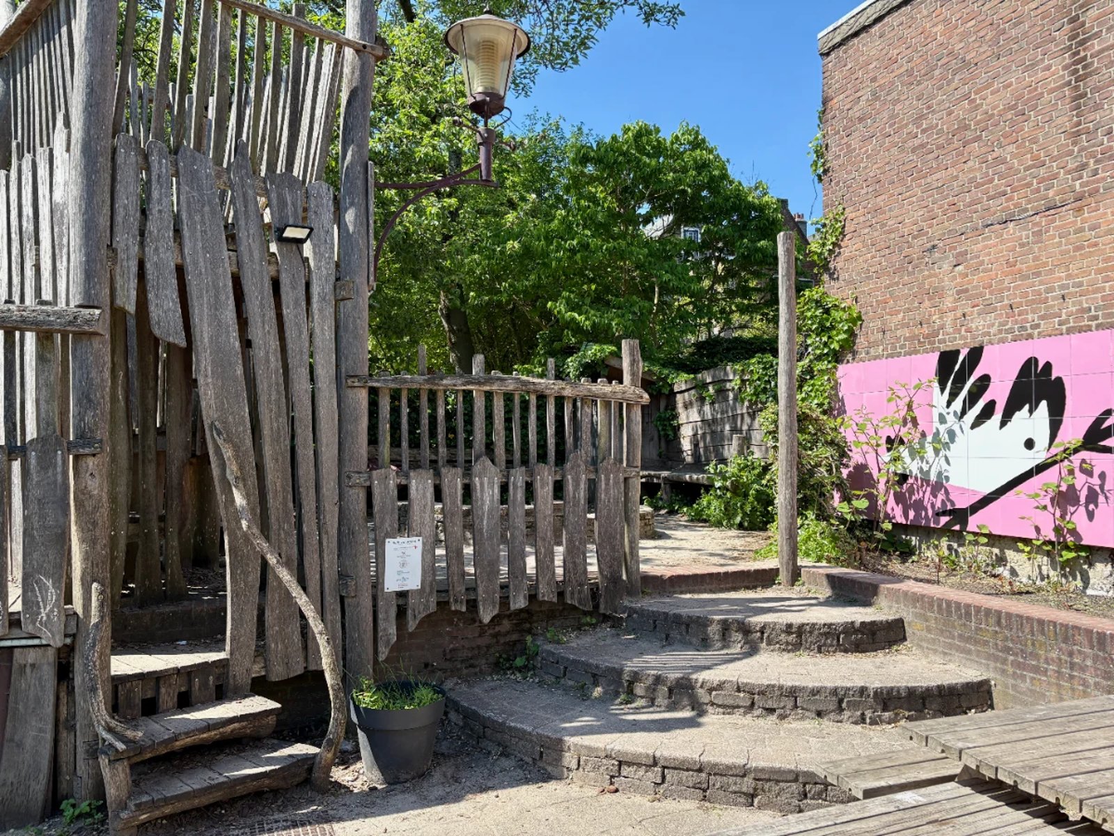 Wooden play house in courtyard with pink mural