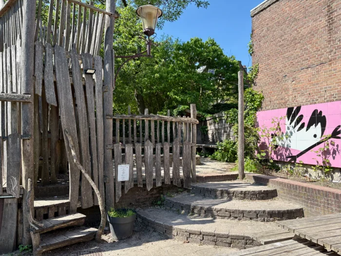 Wooden play house in courtyard with pink mural