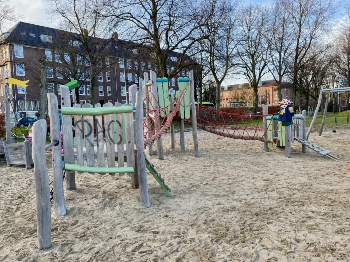 Wooden green and red climbing structure with rope obstacle course
