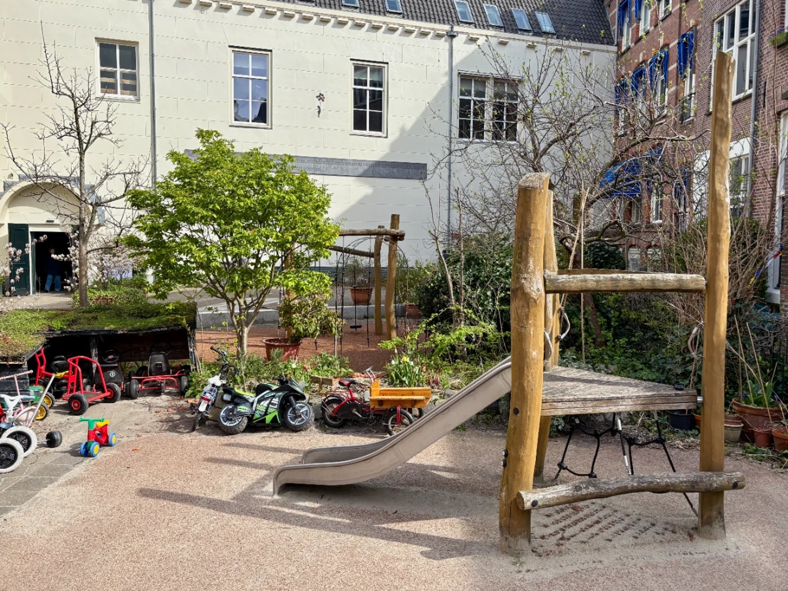 Climbing structure with slide and small shed with lots of kids bikes
