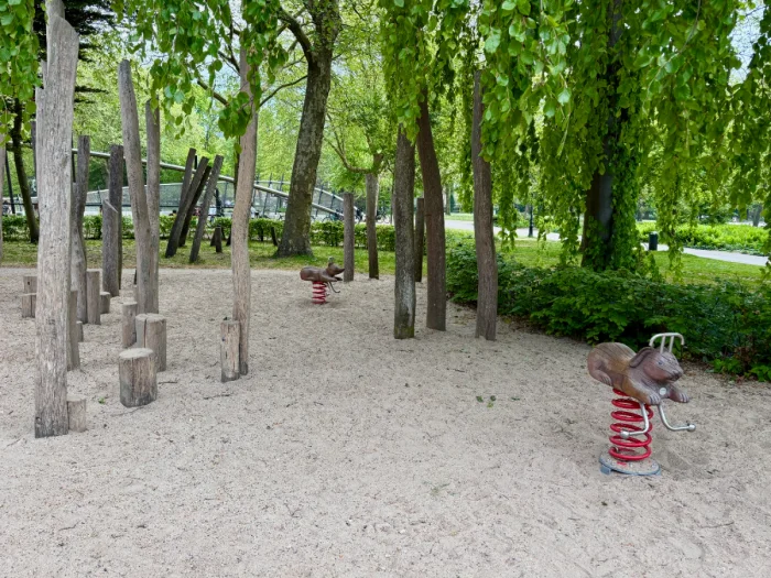 Shaded and sandy playground with natural wood "forest" and animal rockers