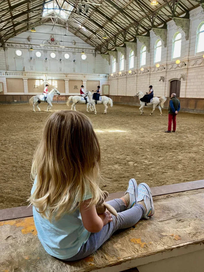 Girl watching horse riding class at the edge of the hall