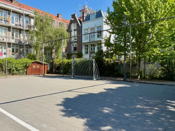 Partially shaded sport court with football goal and residential houses surrounding