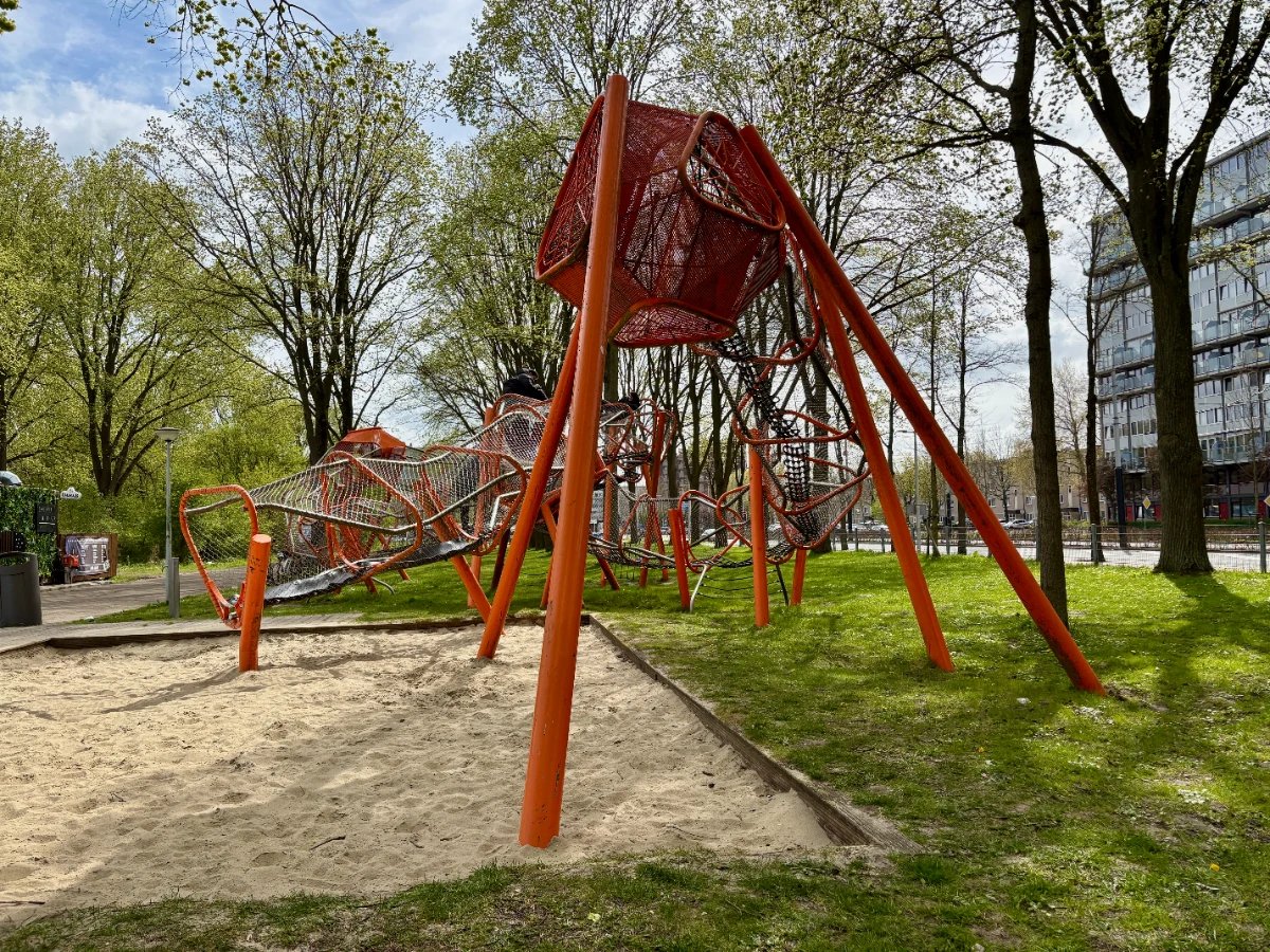 Elevated orange play garland above sand and grass in urban area