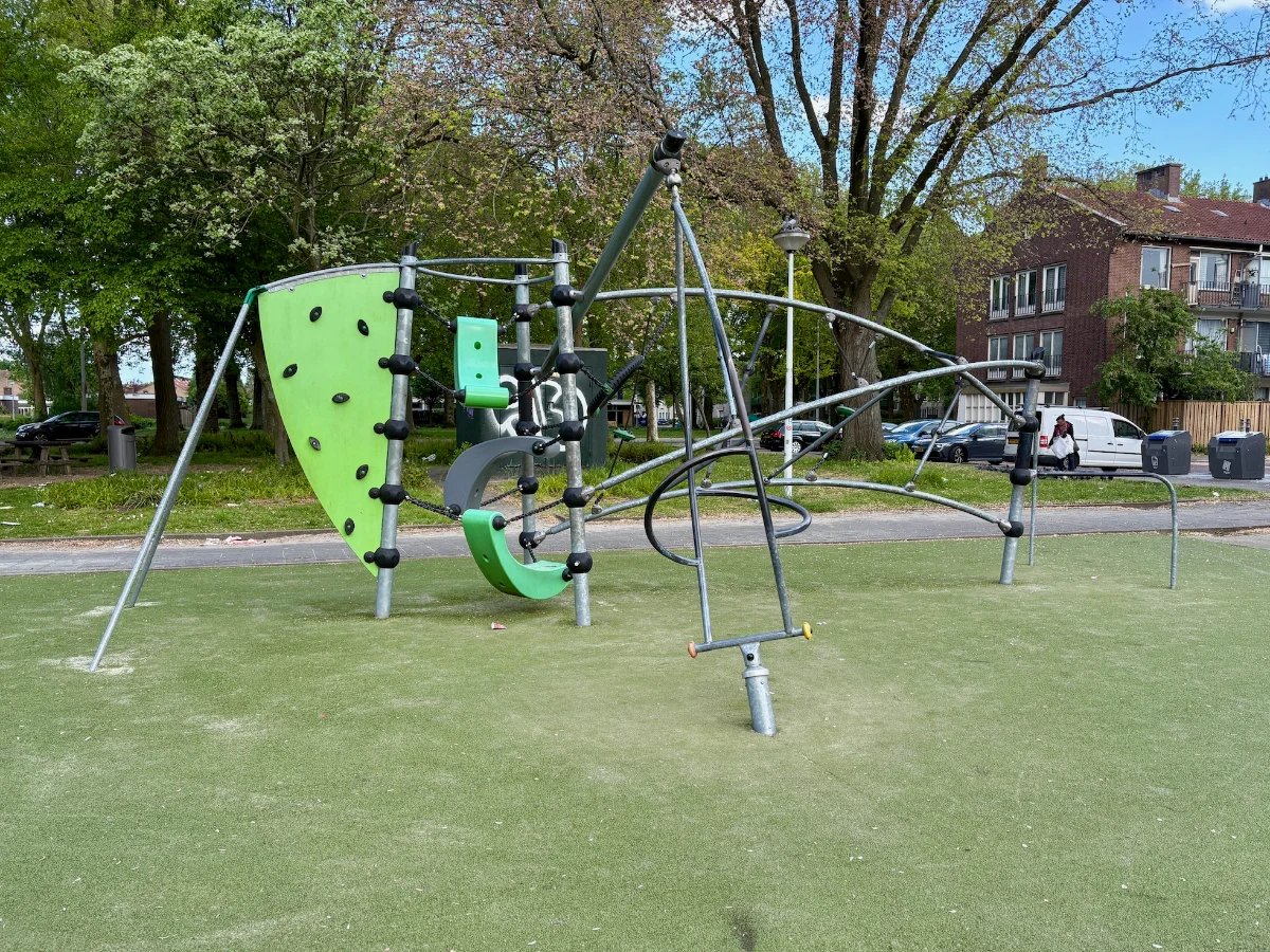 Modern metal climbing structure with lime green accents set in residential area with trees