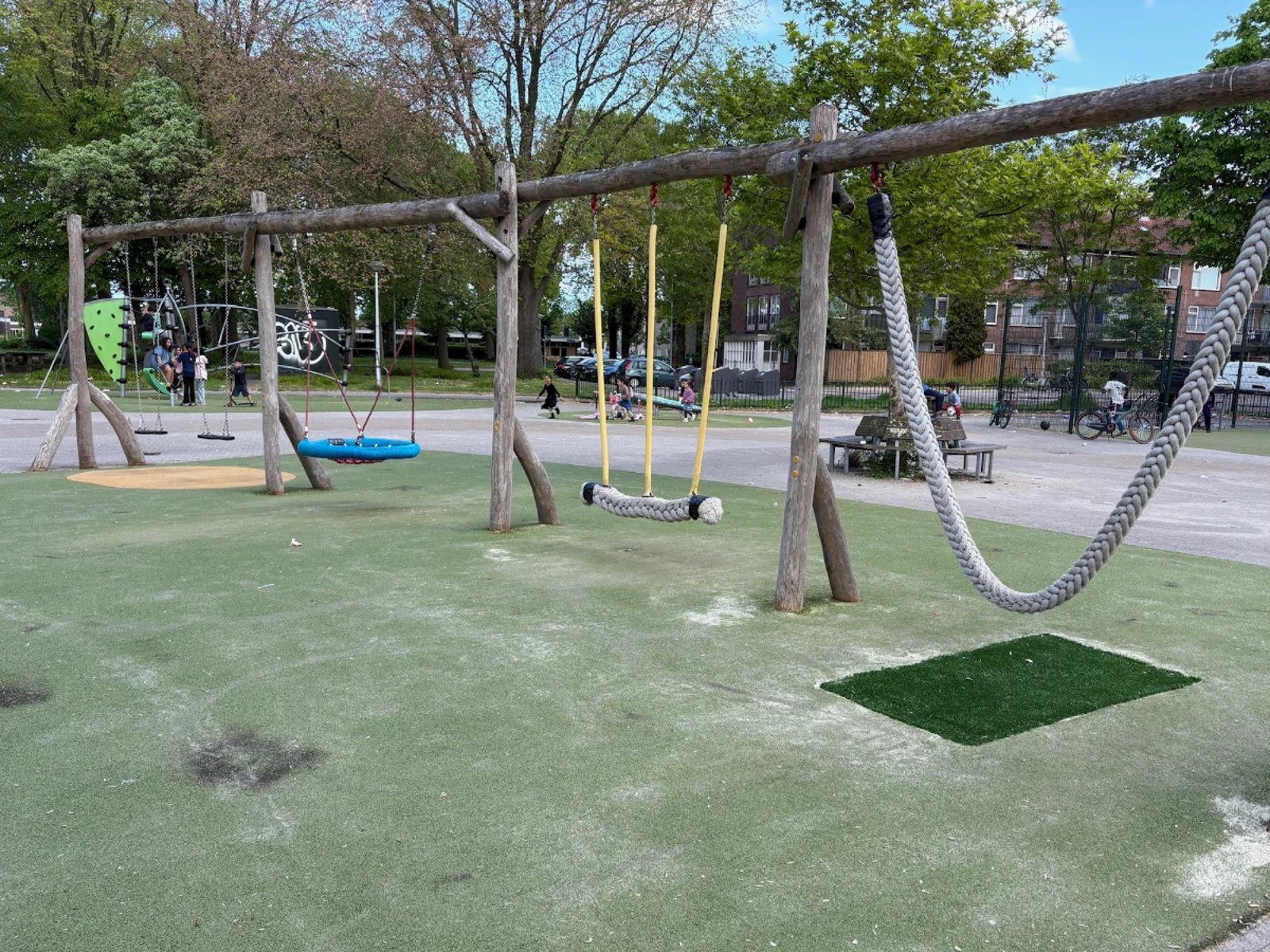 Swing set with a nest swing, two rope swings, and a standard swing set on astroturf