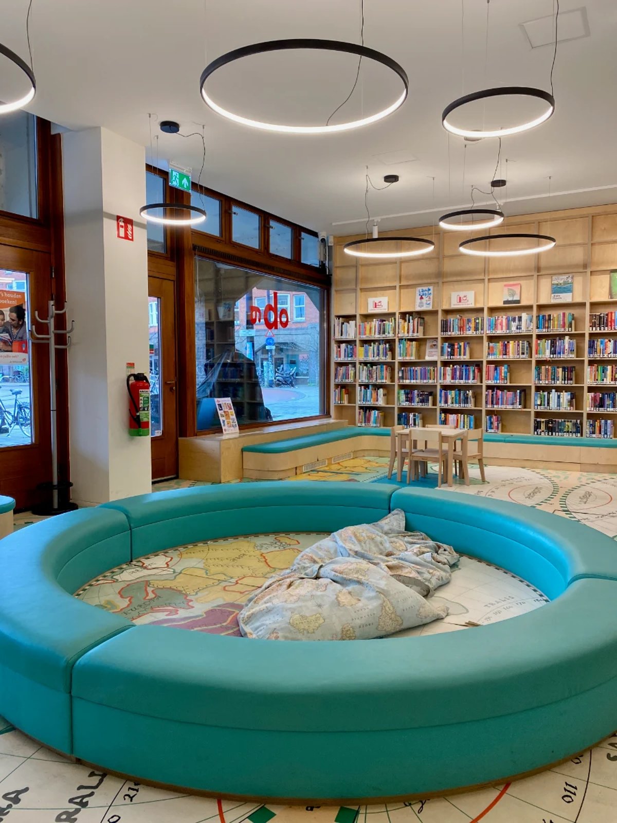 Round play area with pillows for kids with bookshelves and small children's table in the background
