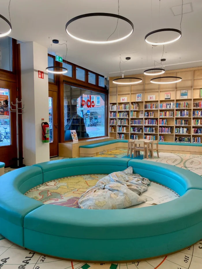 Round play area with pillows for kids with bookshelves and small children's table in the background