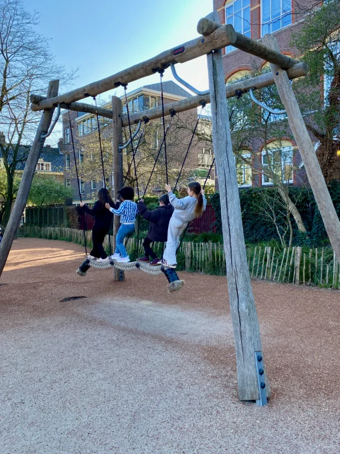 Four kids standing on rope swing