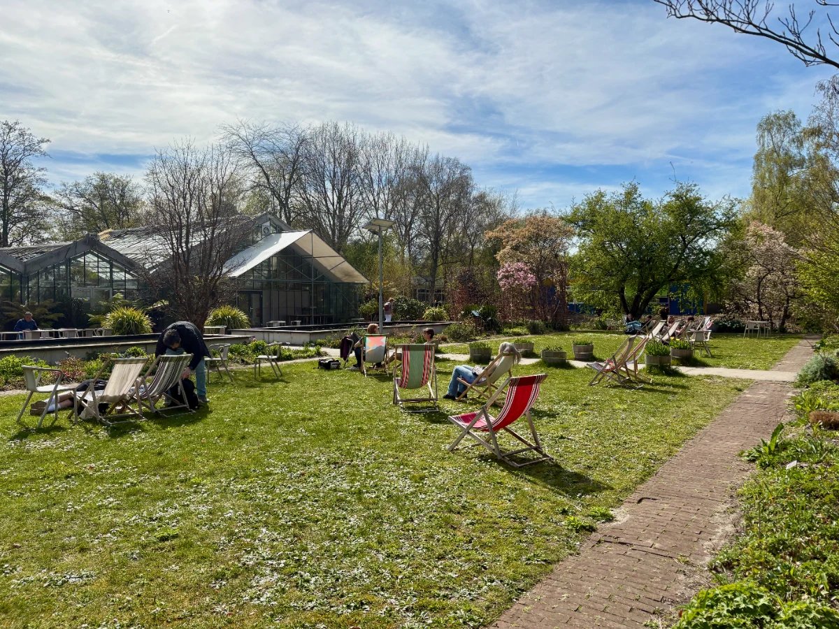 Greenhouses and lawn with people lounging in the sun in folding chairs