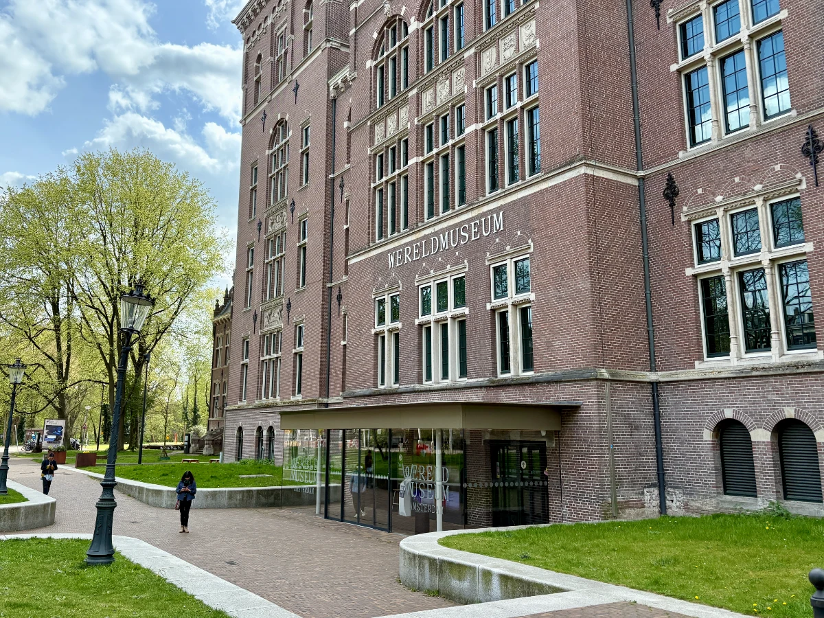 Stately brick museum building with modern glass entrance and grassy lawn and trees in front