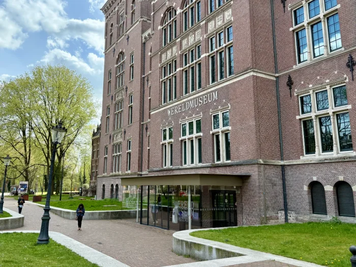 Stately brick museum building with modern glass entrance and grassy lawn and trees in front