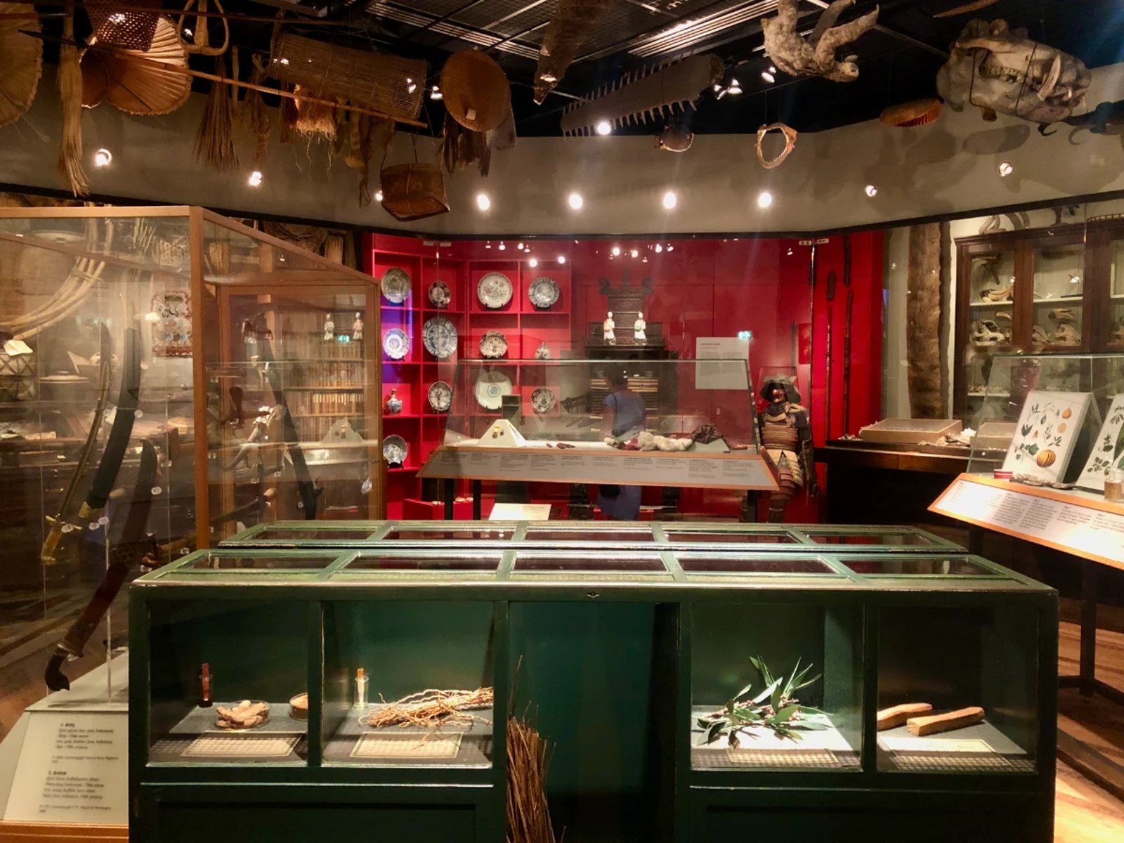 Green display cabinet and red accent wall with artefacts on displace