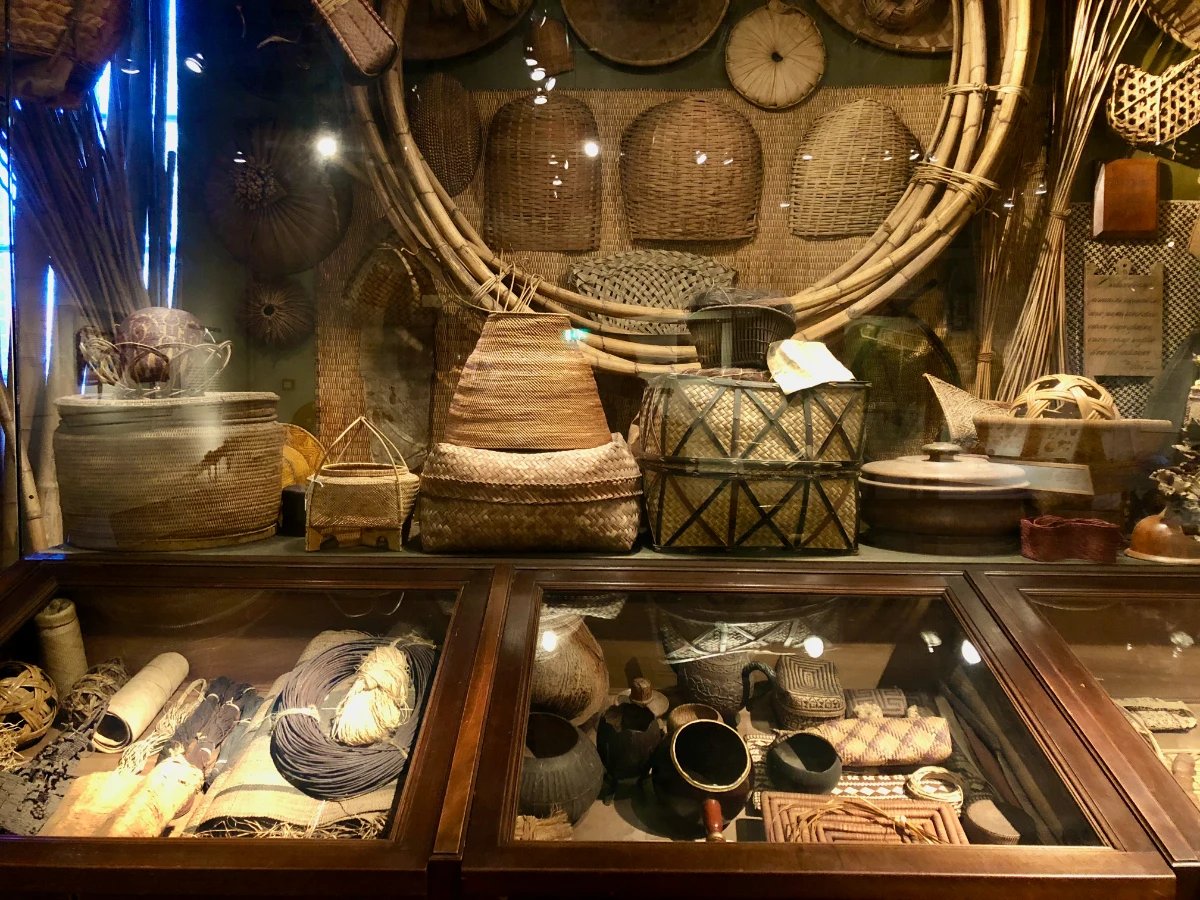 Museum display of various woven baskets on the wall and in a display case