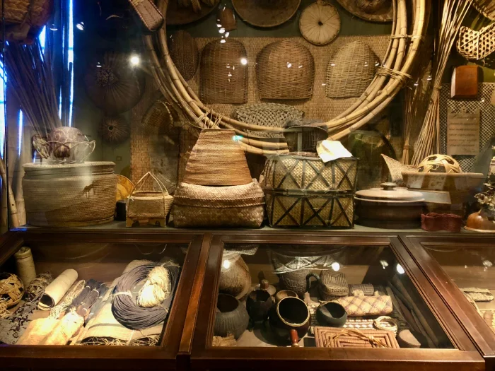 Museum display of various woven baskets on the wall and in a display case