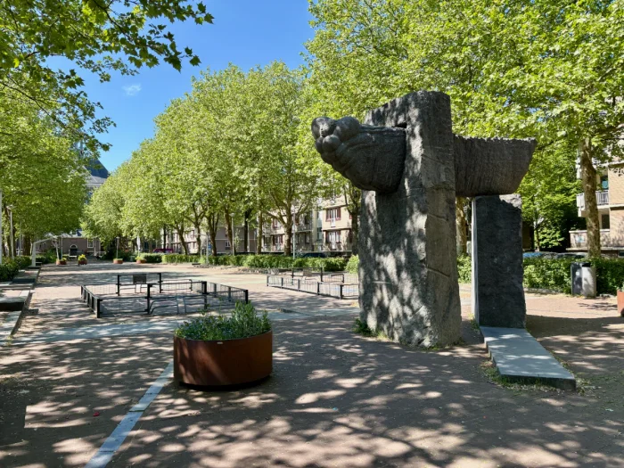 Large modern stone sculpture in shaded plaza with two mini football pitches and large trees