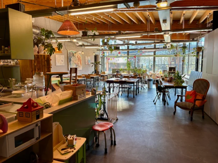 Warm restaurant interior with tables and chair, wooden beams overhead, and counter with a few toys