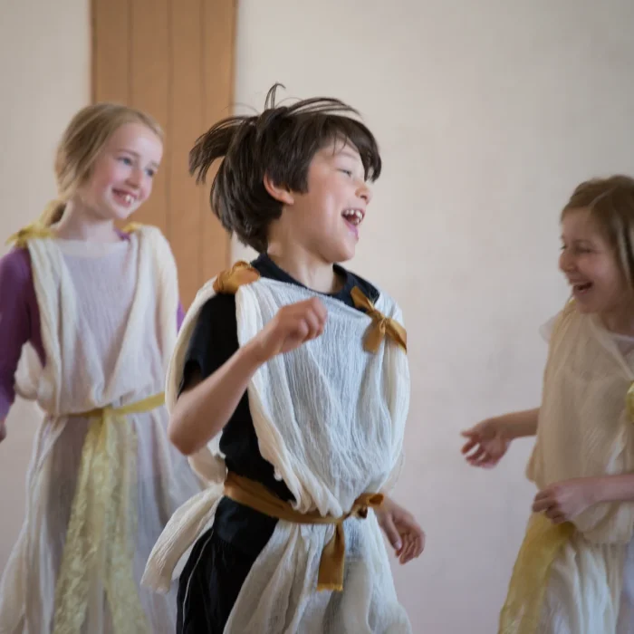 Boy and two girls in costumes dancing and smiling