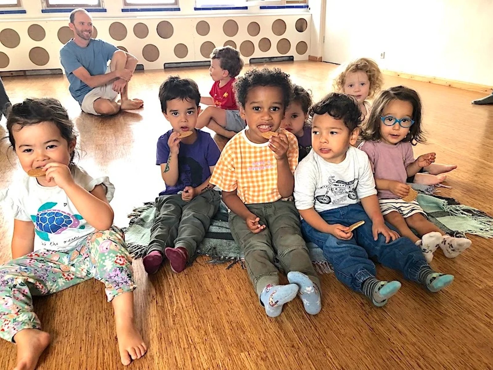 Group of kids sitting on the floor having a snack in a dance studio space