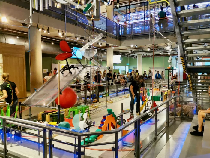 Kids watching museum workers set up Rube Goldberg machine in atrium