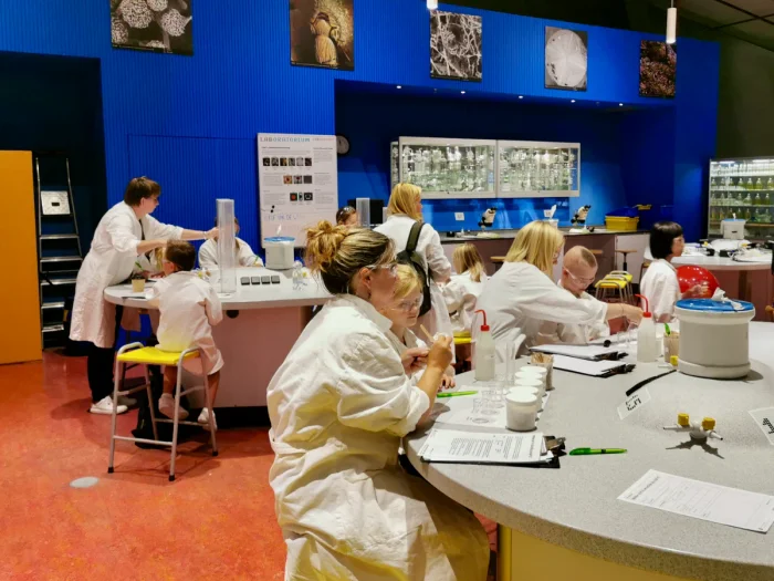 Children and parents dressed in lab cost and sitting at tables doing science experiments
