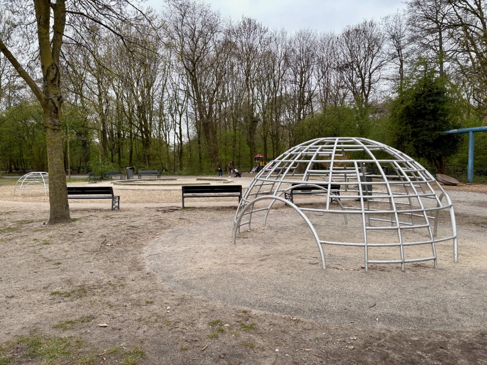 Kids playground with climbing igloo, sandbox and benches in a park