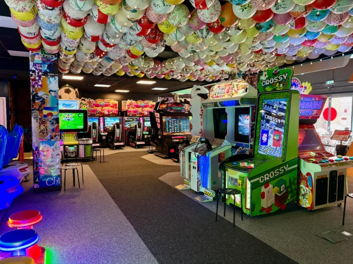 Arcade with neon lights and anime posters around arcade games with colorful paper lanterns on the ceiling