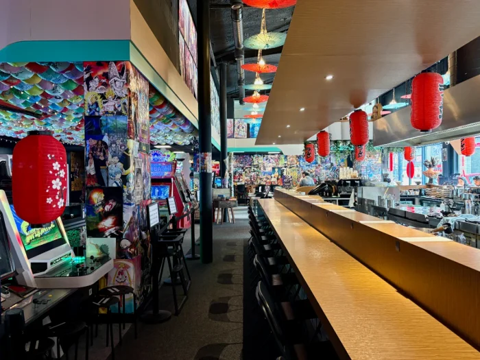 Long ramen bar with red paper lanterns with arcade games to the side