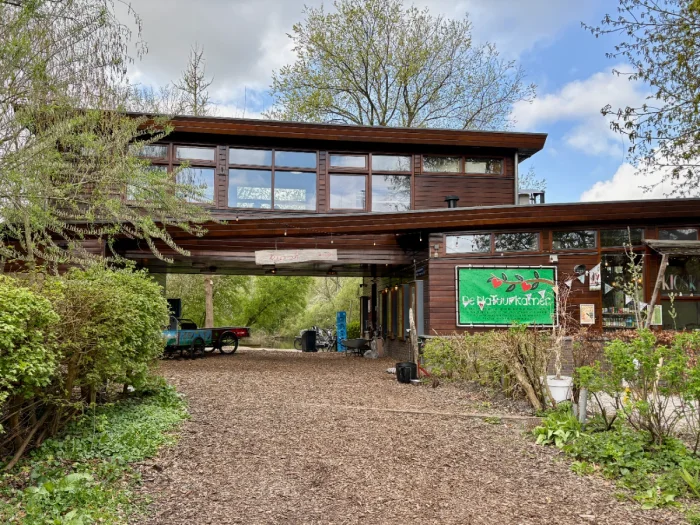 Community center building spanning pathway through park with large green sign