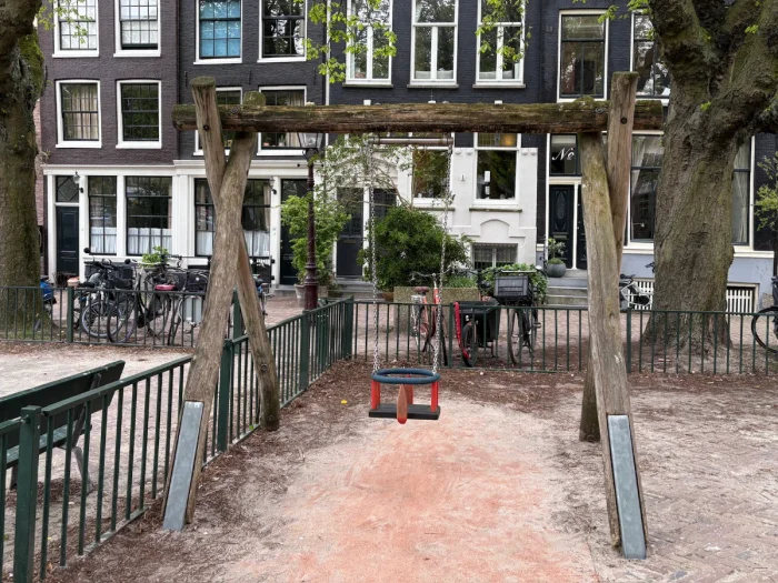 Small wooden frame with baby swing next to fence and Dutch houses