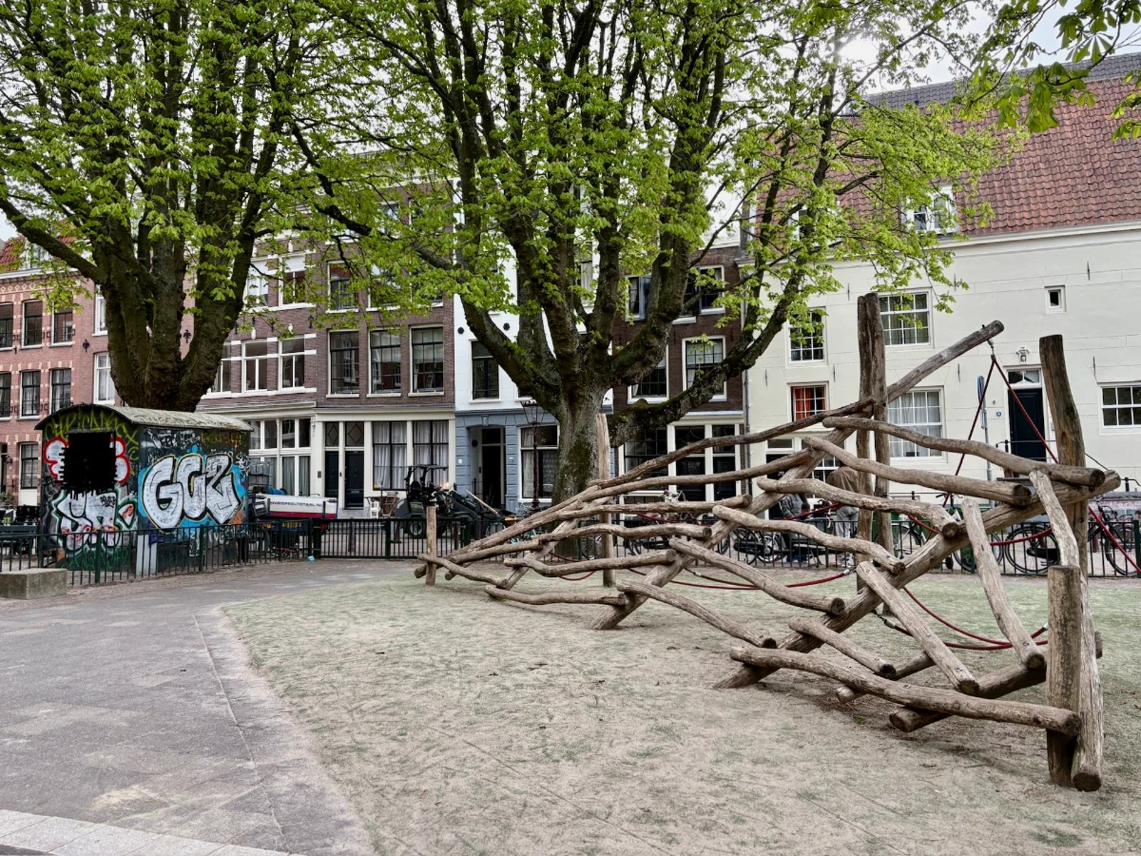 Rustic climbing structure made of angled logs in residential area shaded by mature trees