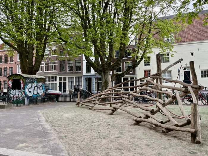 Rustic climbing structure made of angled logs in residential area shaded by mature trees 