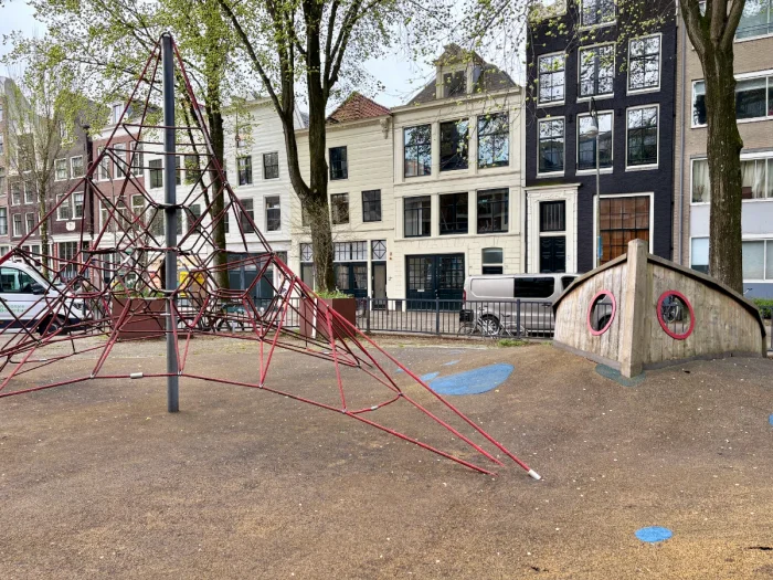 Playground with red rope climbing pyramid and play boat set in residential area
