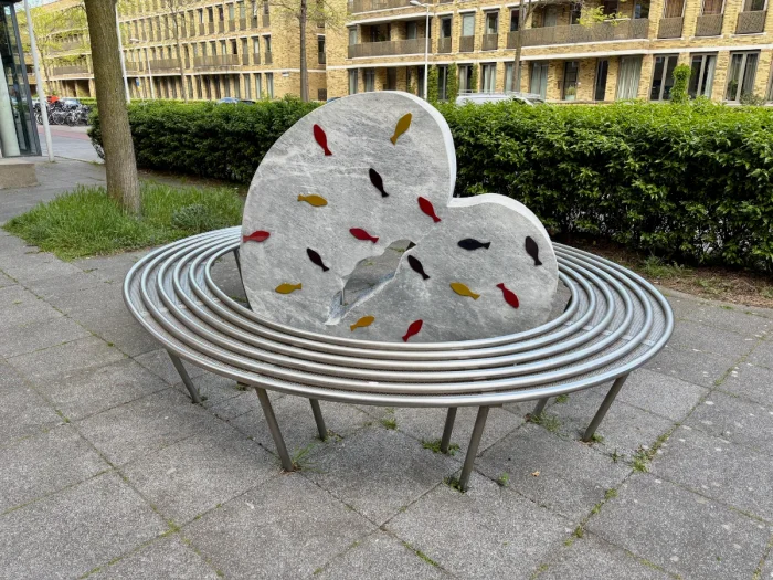 Round bench with stone sculpture in the center adorned with fish