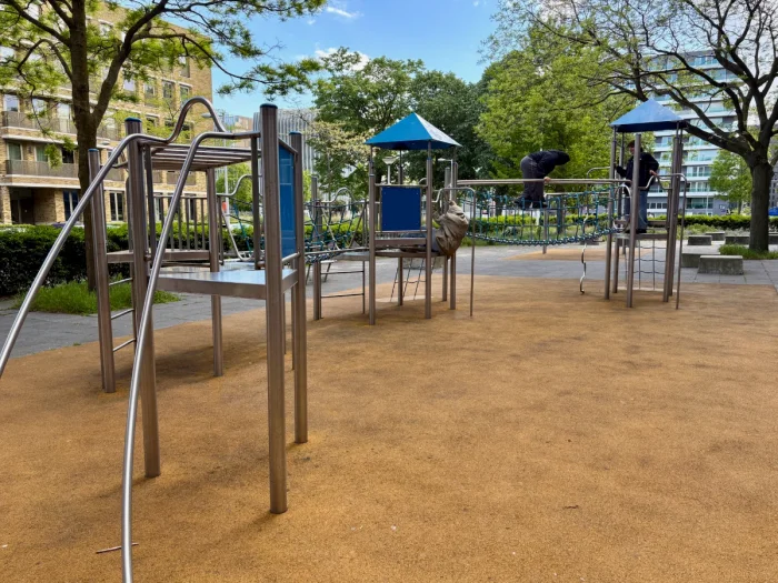 Modern metal play structure with a variety of climbing and balance challenges set in residential area