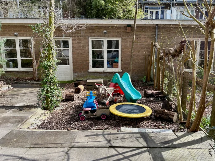 Small garden in courtyard with toddler slide, trampoline, and other outdoor toys