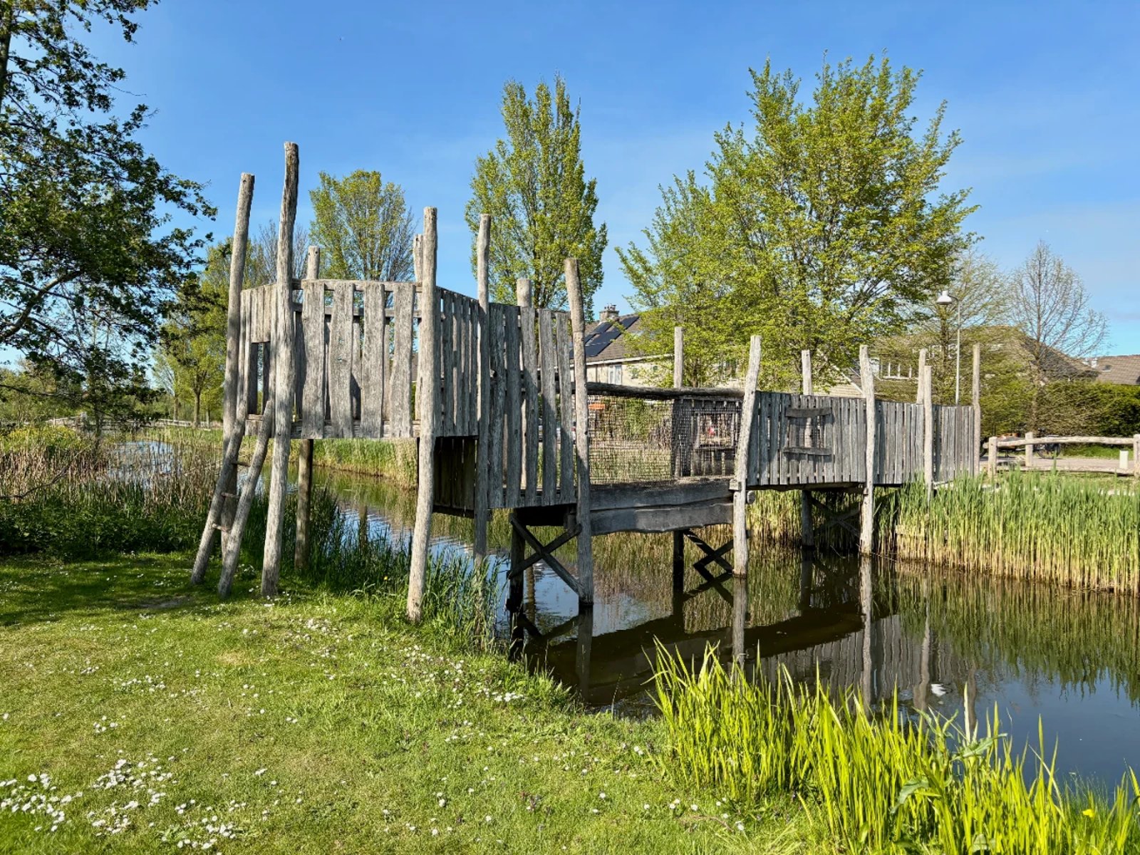 Rustic wooden bridge with different heights and ladders spanning canal