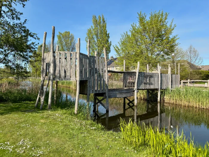 Rustic wooden bridge with different heights and ladders spanning canal
