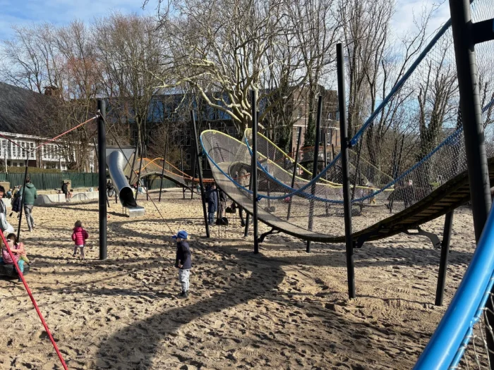 Children play beneath large undulating elevated play structure
