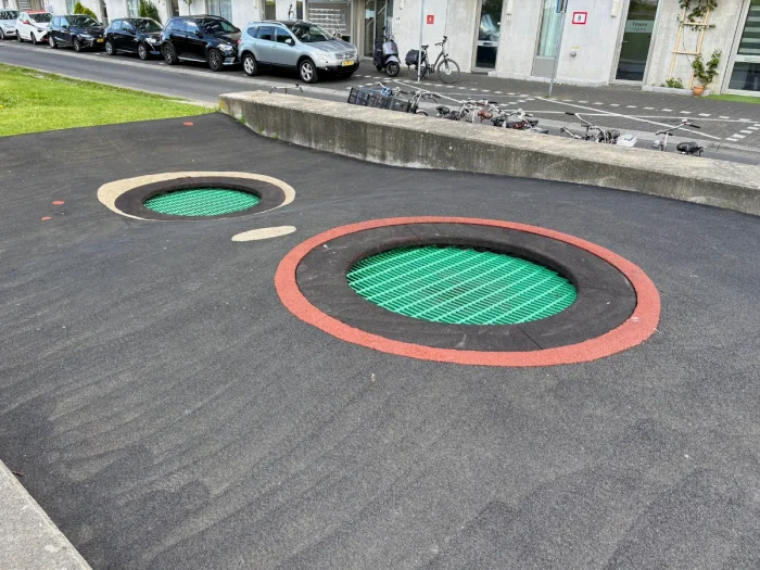 Round green outdoor trampolines outlined with red stripe set on black surface